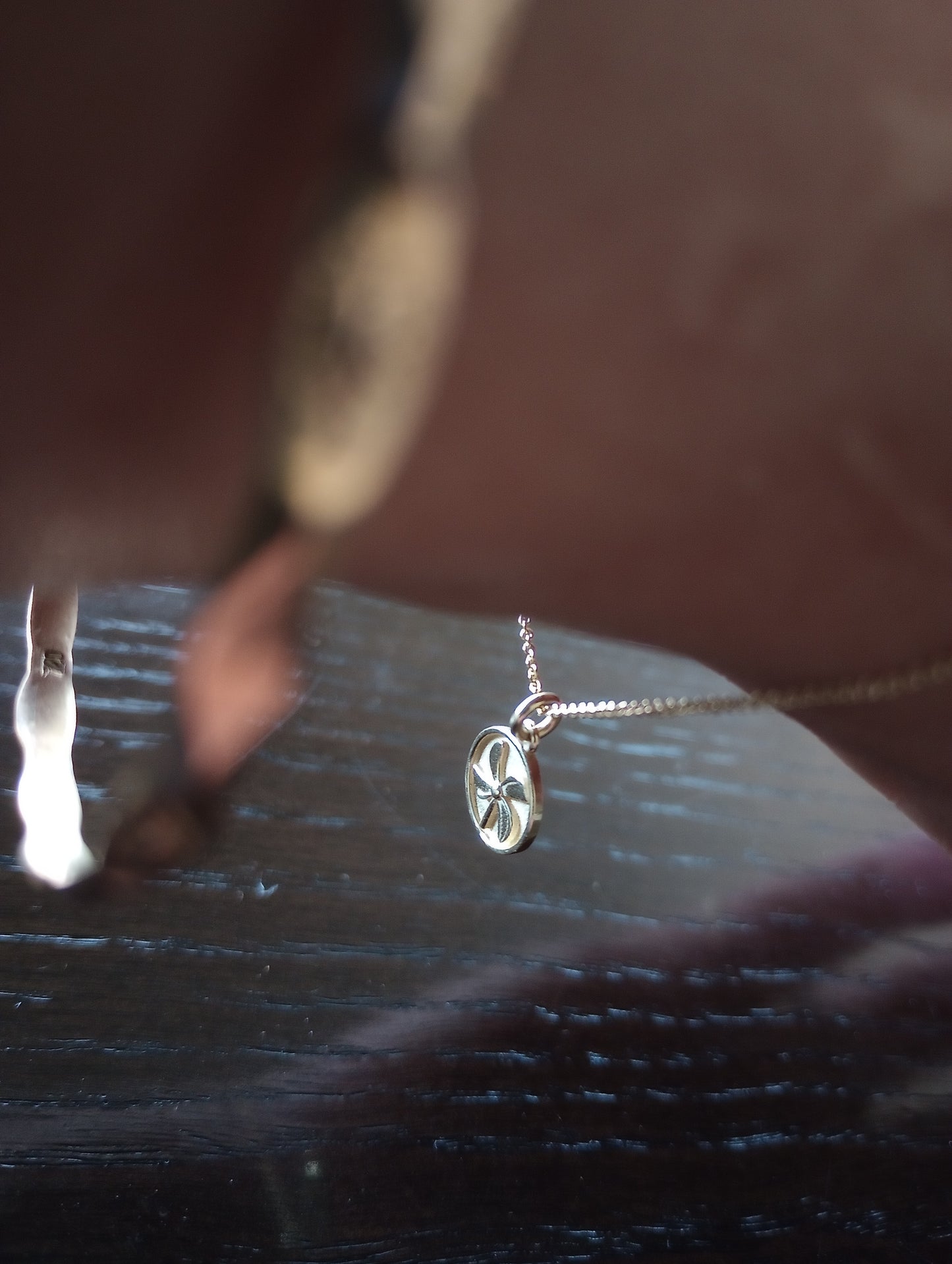 Gold Feels Like Fun® Pinwheel Pendant held in hand, showcasing its handcrafted circular design with symbolic spiral blades.